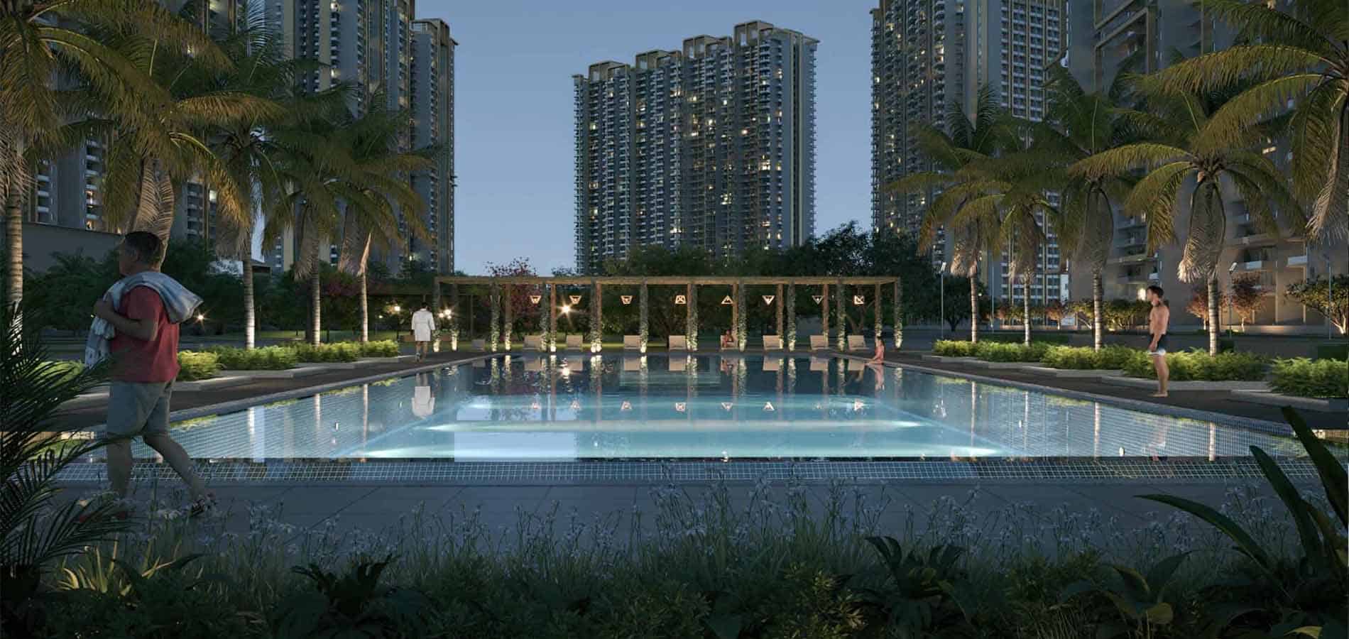 Luxurious outdoor swimming pool area illuminated at night, surrounded by palm trees and high-rise apartments